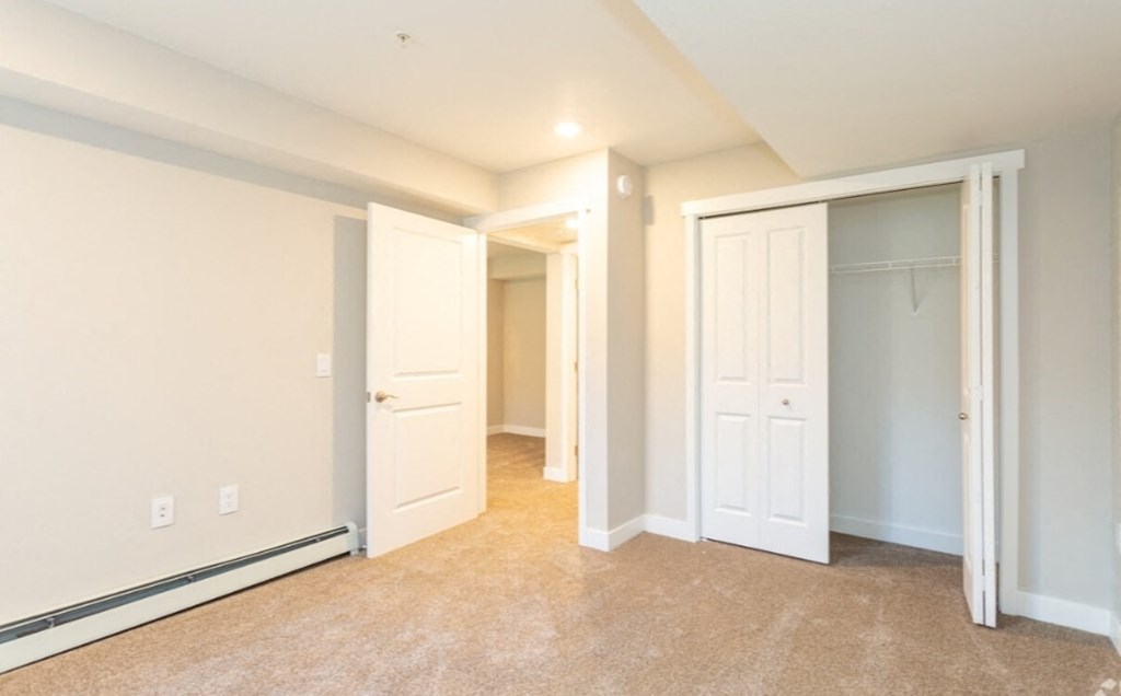an empty bedroom with two closets and a carpeted floor