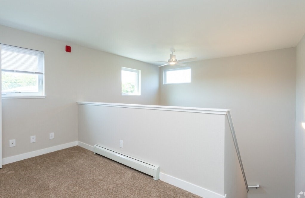a bedroom with a white wall and a ceiling fan