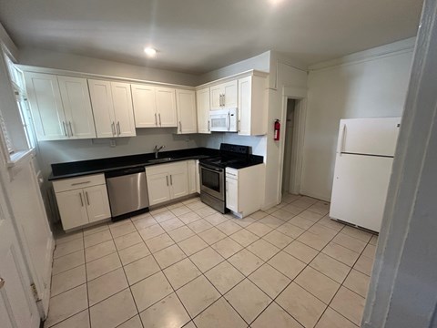 A kitchen with white cabinets and black countertops.