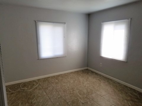 an empty room with two windows and a tiled floor
