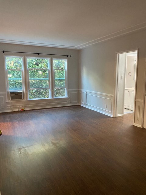 an empty living room with wood floors and a window