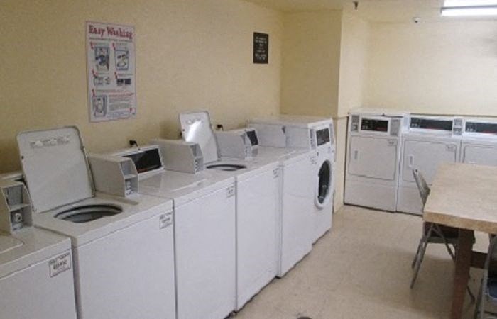 a row of washing machines and dryers in a laundry room
