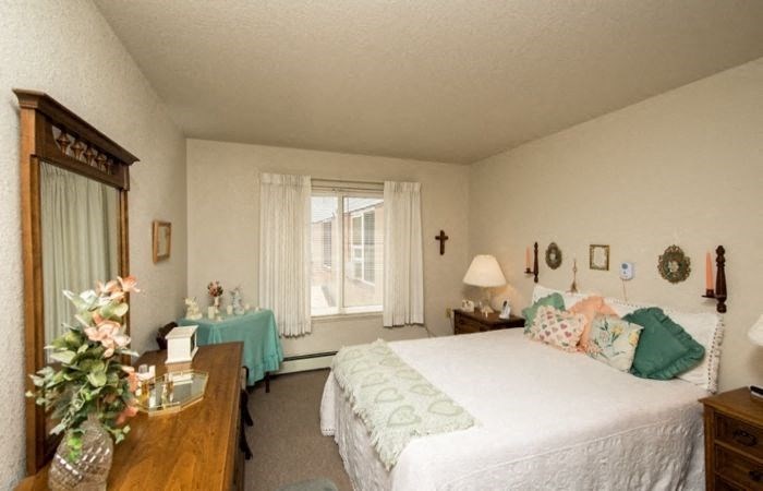 a bedroom with a bed and a table and a window