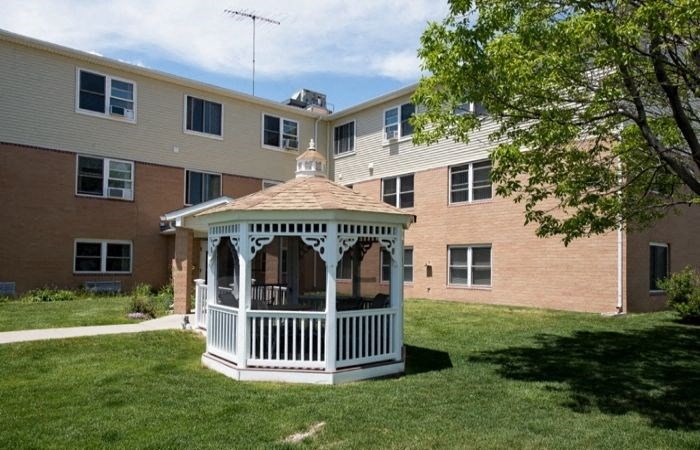 a gazebo in a yard in front of an apartment building