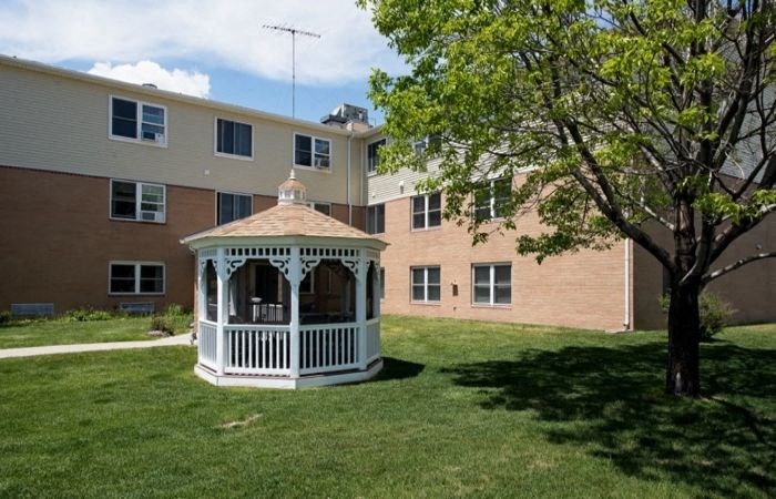 a gazebo in a yard in front of an apartment building