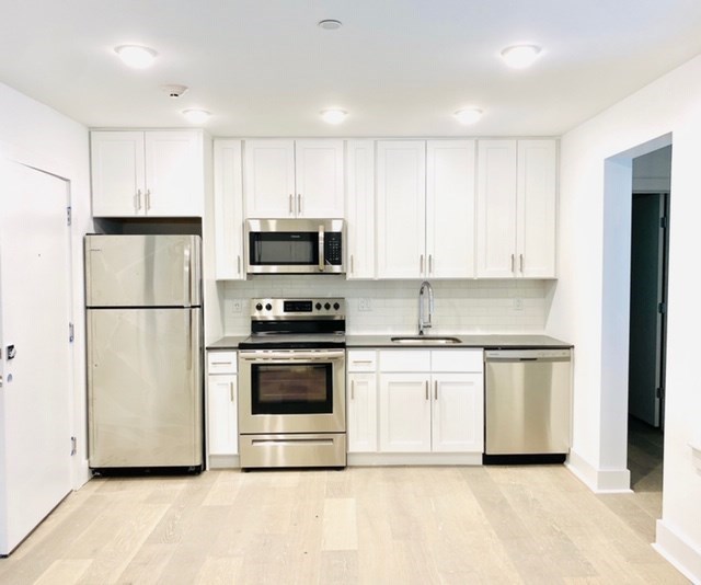 an empty kitchen with stainless steel appliances and white cabinets