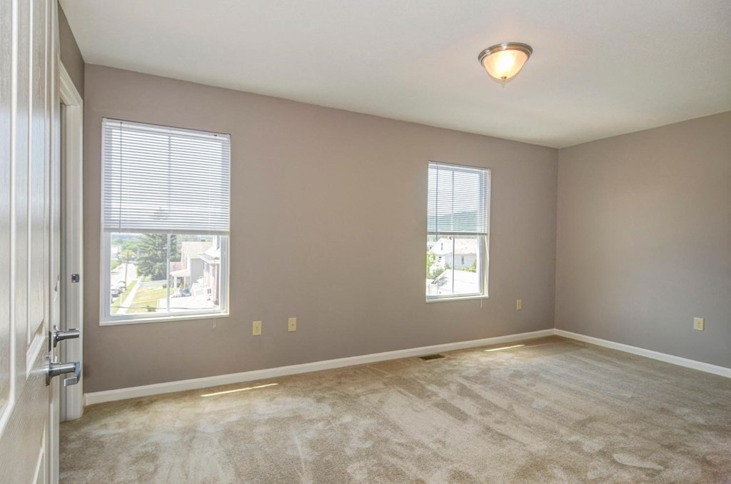 a living room with a carpeted floor and two windows