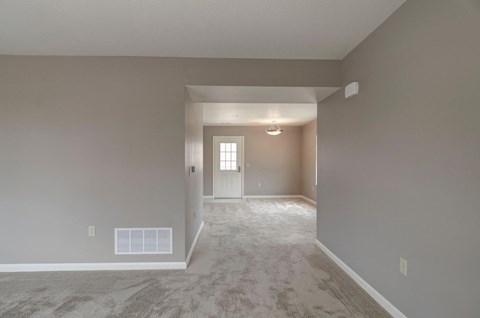 a empty living room with a white carpet and a white door