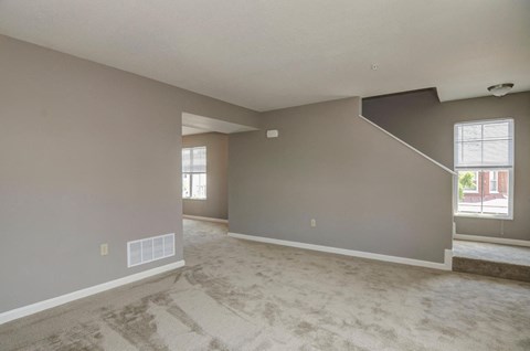 the living room and dining room of an empty house with a carpeted floor