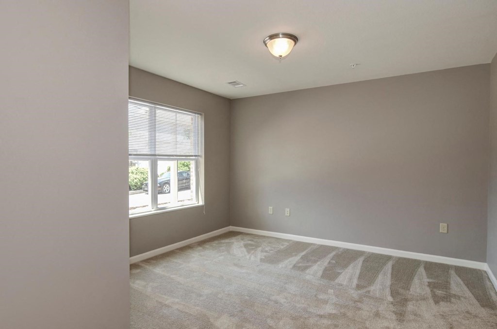 an empty living room with a window and carpet