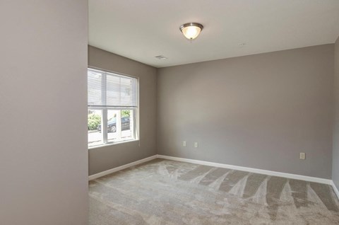 an empty living room with a window and carpet