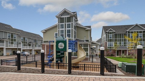 a playground with a slide in front of an apartment building