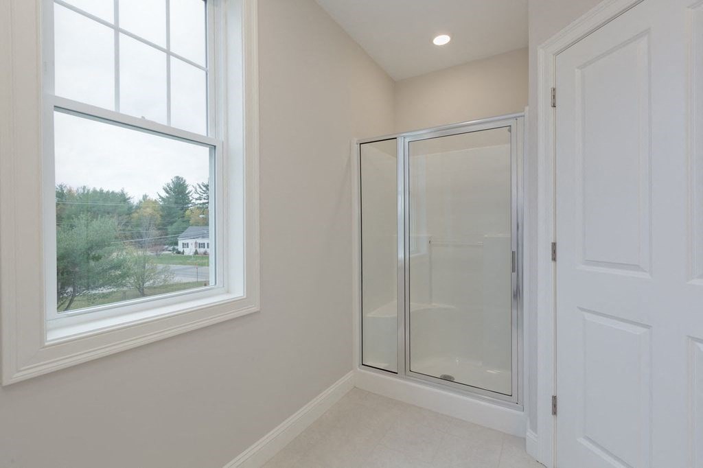 a white bathroom with a shower and a window