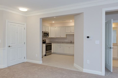 an empty kitchen with white cabinets and a white door