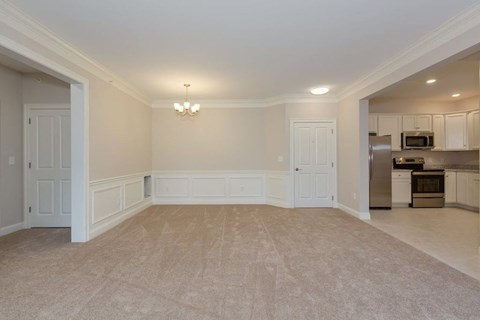 an empty living room and kitchen with white walls