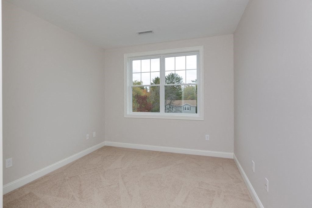 an empty bedroom with a window and a carpeted floor