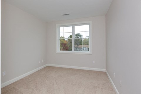 an empty bedroom with a window and a carpeted floor