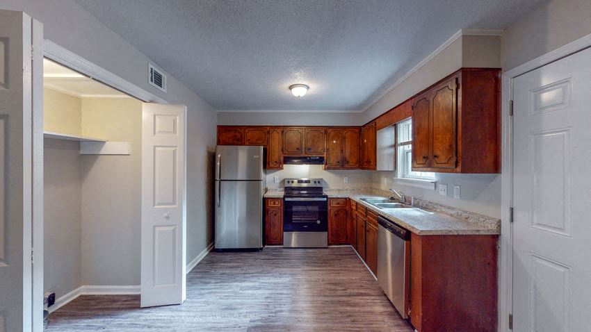 an empty kitchen with wooden cabinets and a refrigerator