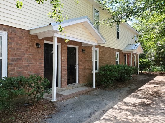 a brick house with two doors and a sidewalk