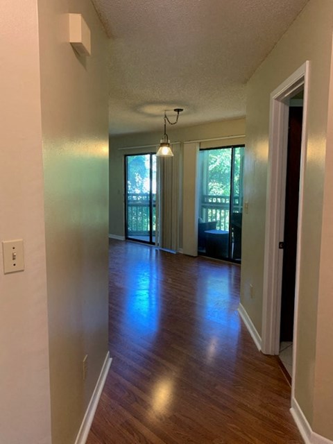 A long hallway with a door on the right and a window on the left.