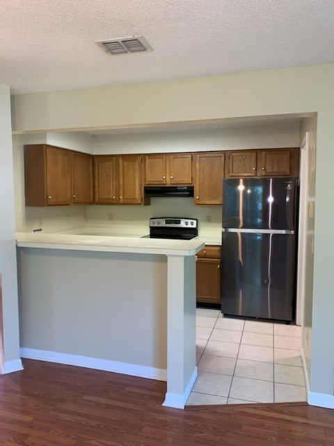 A kitchen with wooden cabinets and a stainless steel refrigerator.