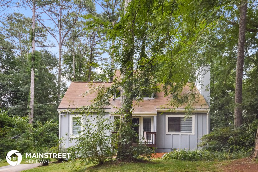 a small white house with a tree in front of it