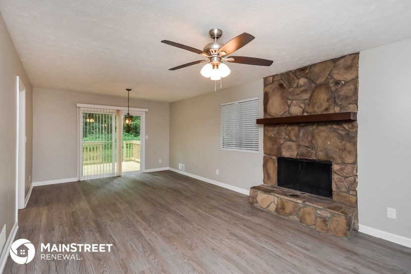a living room with a stone fireplace and a ceiling fan