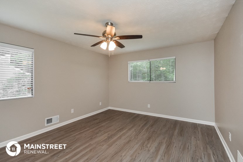 the spacious living room with ceiling fan and wood flooring