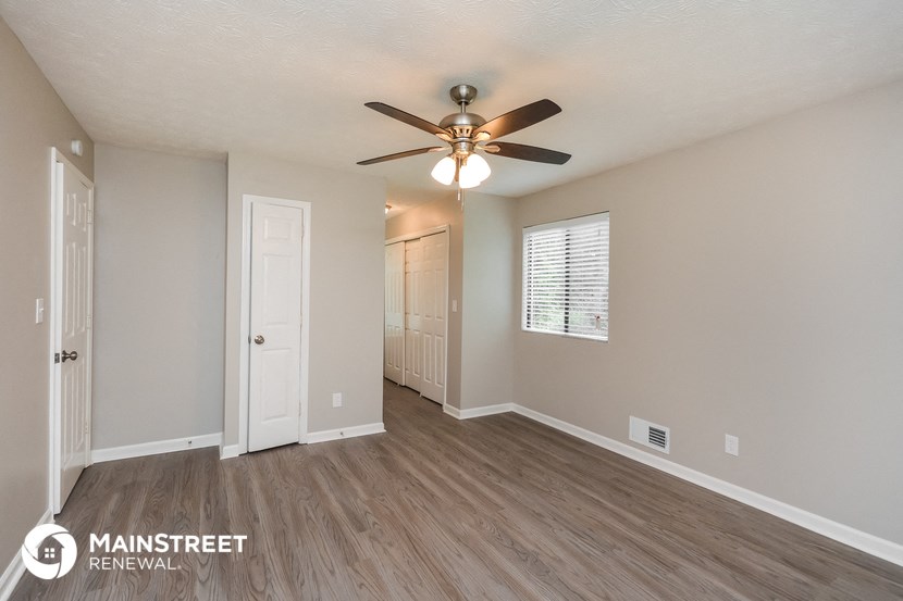 the living room is spacious and has a ceiling fan