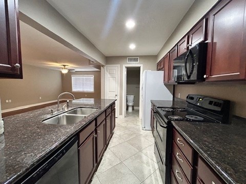 A kitchen with brown cabinets and a black counter top.