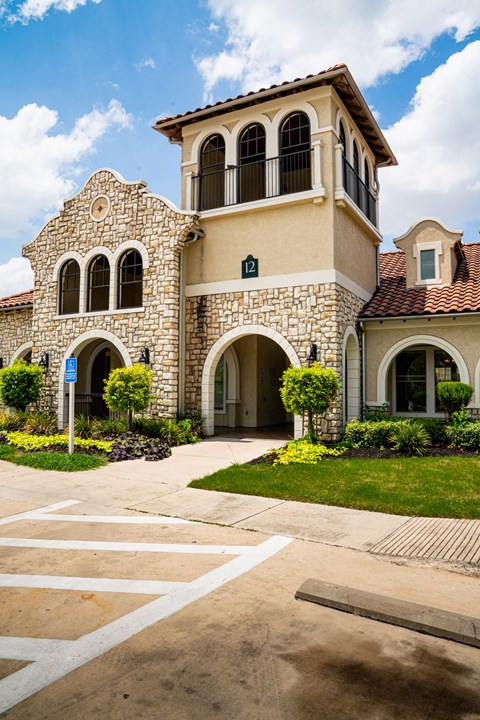 the front of a building with a walkway and a tower