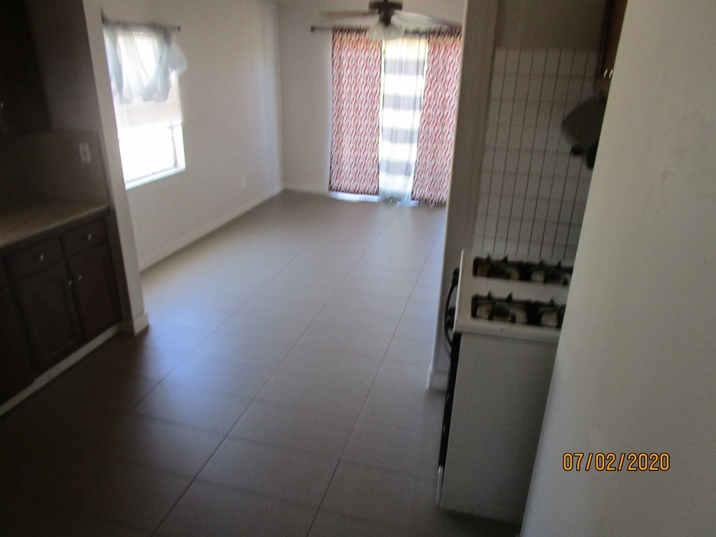 A kitchen with a white fridge and a window with red curtains.