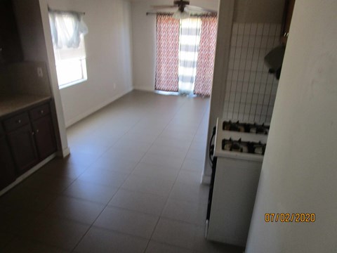 A kitchen with a white fridge and a window with red curtains.