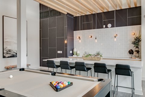 a kitchen with a pool table and black chairs