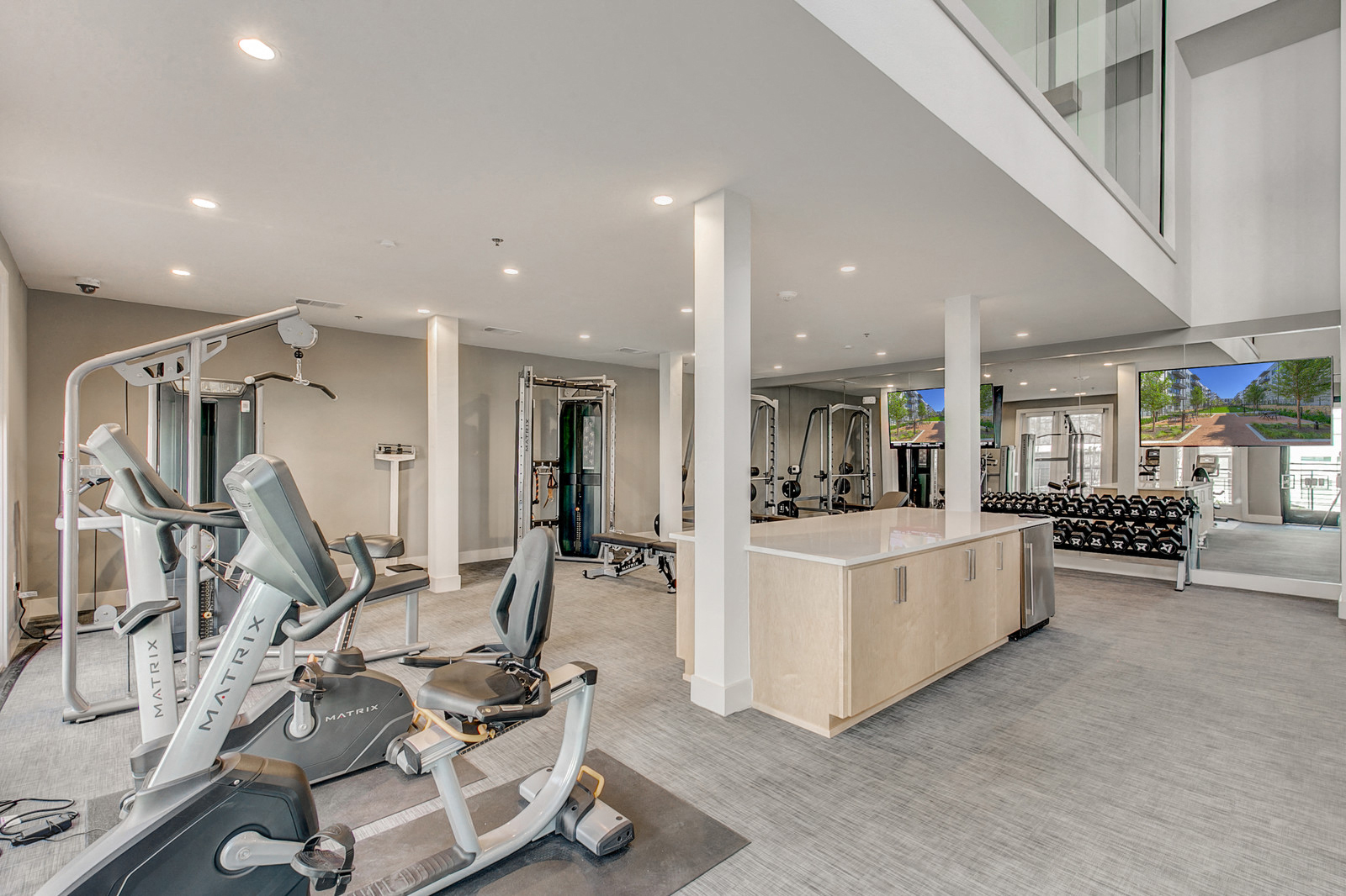 a gym with exercise equipment and a bar in a building with windows