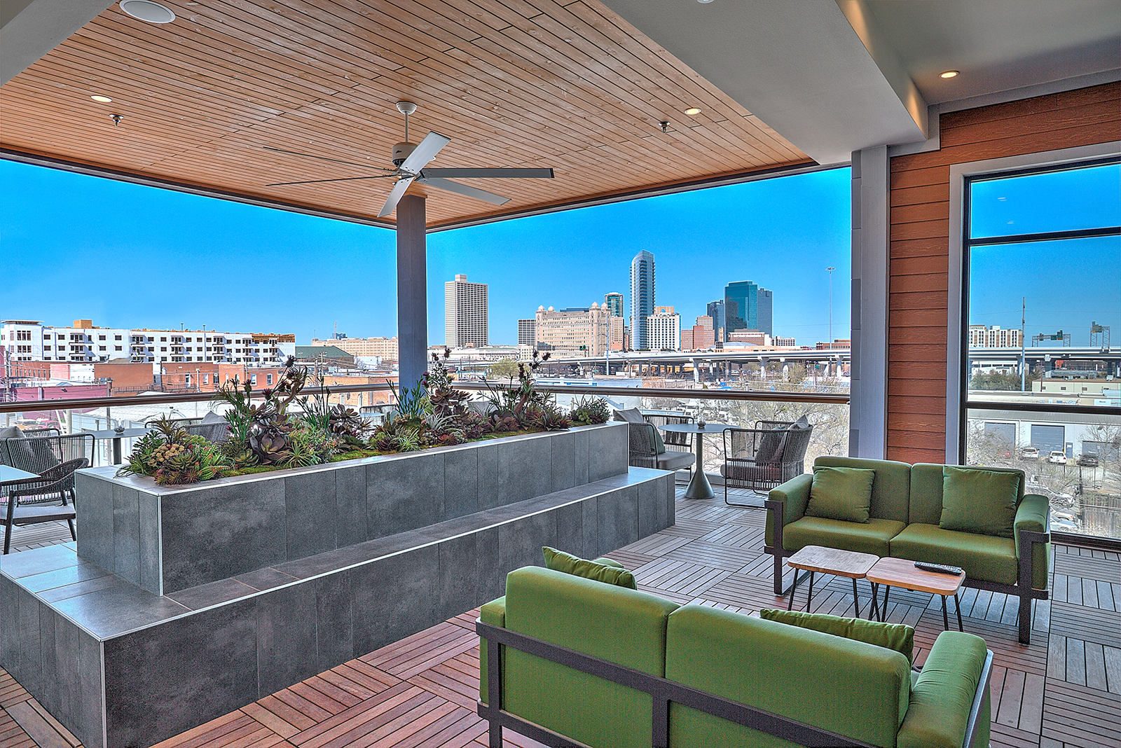 a balcony with a view of a city and a patio with green furniture