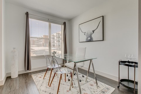 a dining room with a glass table and chairs and a large window