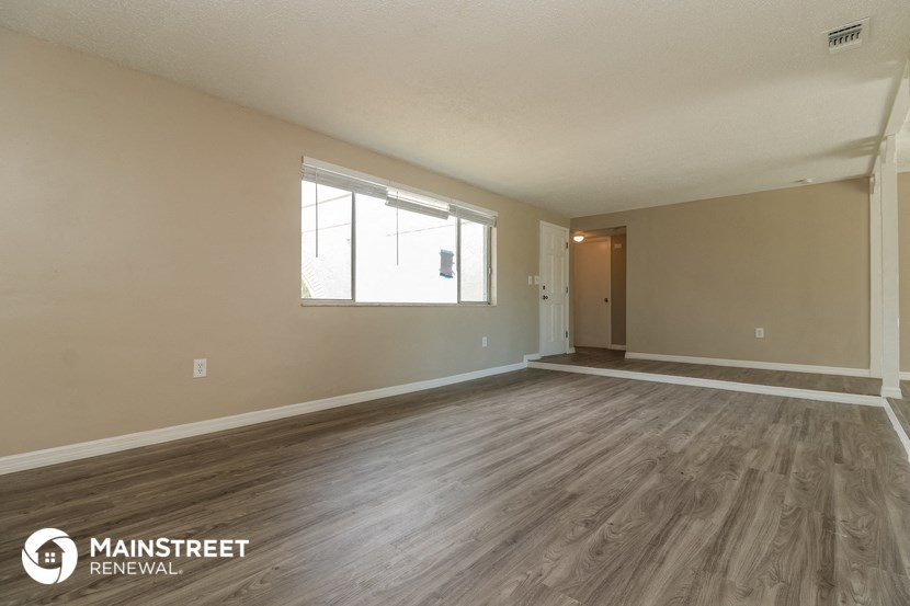 the spacious living room with hardwood flooring and a large window