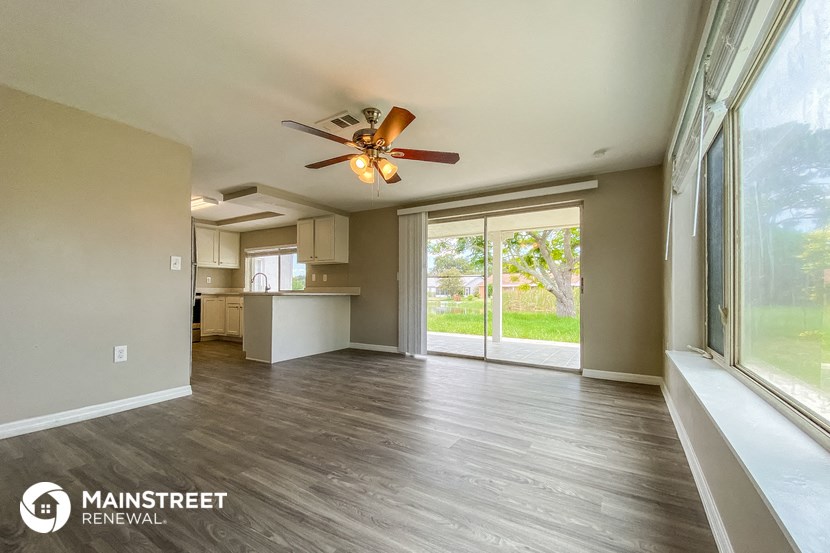 a living room with a large window and a ceiling fan