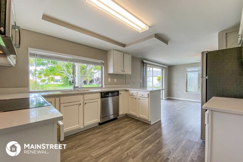 a kitchen with white cabinets and a large window