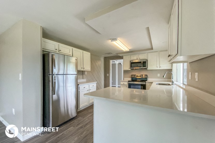 a white kitchen with stainless steel appliances and white counter tops