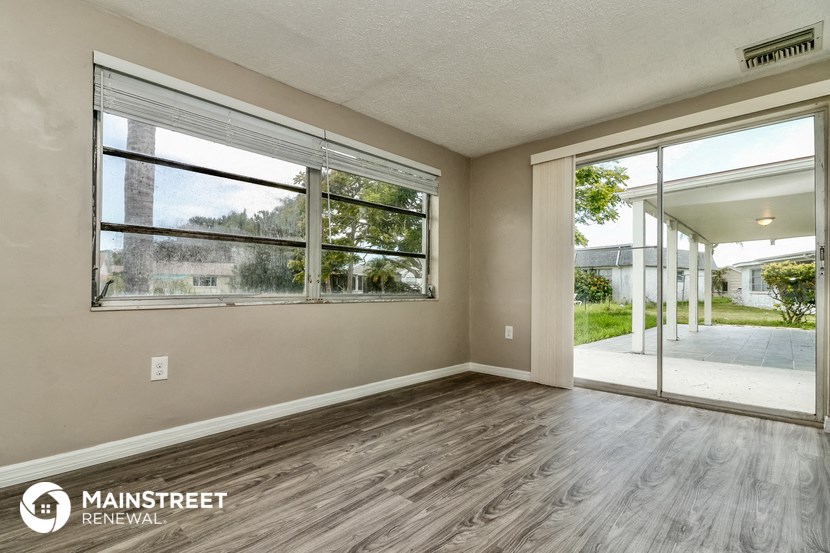 an empty living room with a large window and wood flooring
