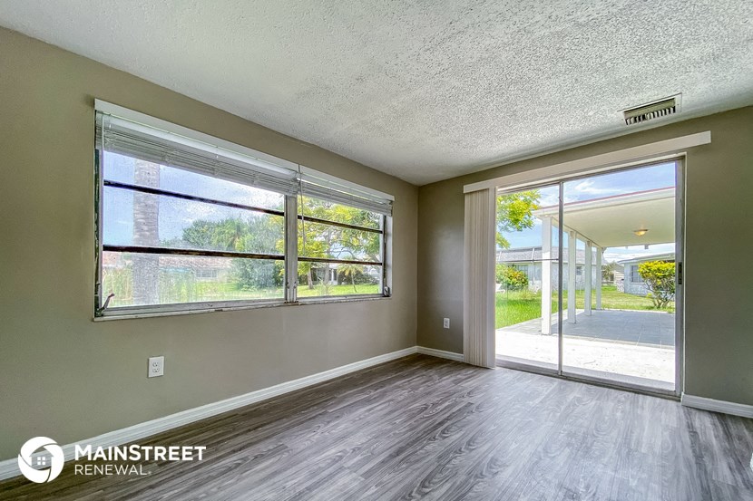 an empty living room with large windows and wood flooring