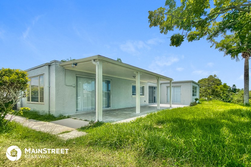 a small white house with a porch and a grassy yard