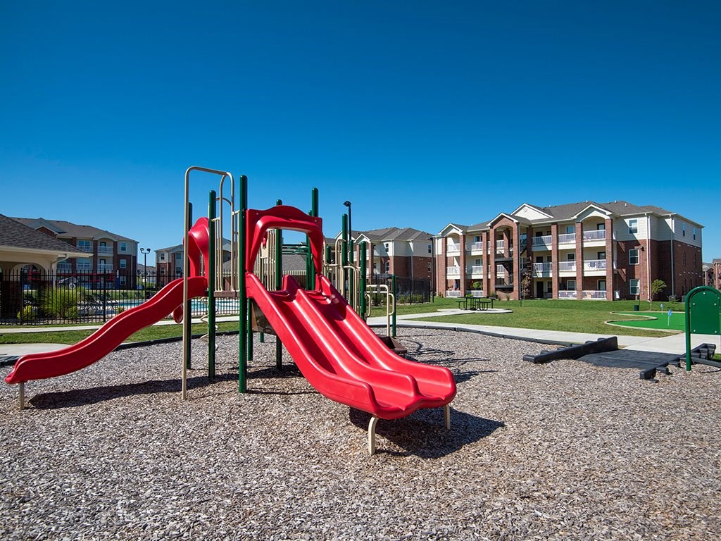 a playground with slides and buildings in the background