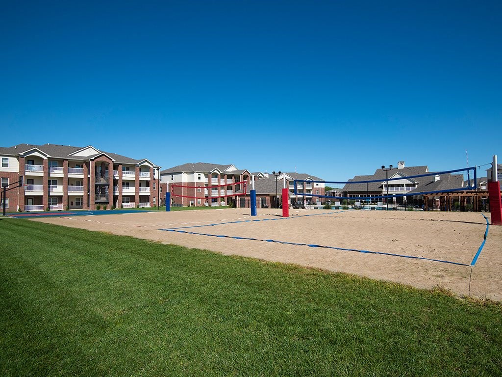 a sand volleyball court with apartments in the background