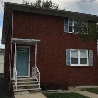 A red brick house with a white door and a white porch.