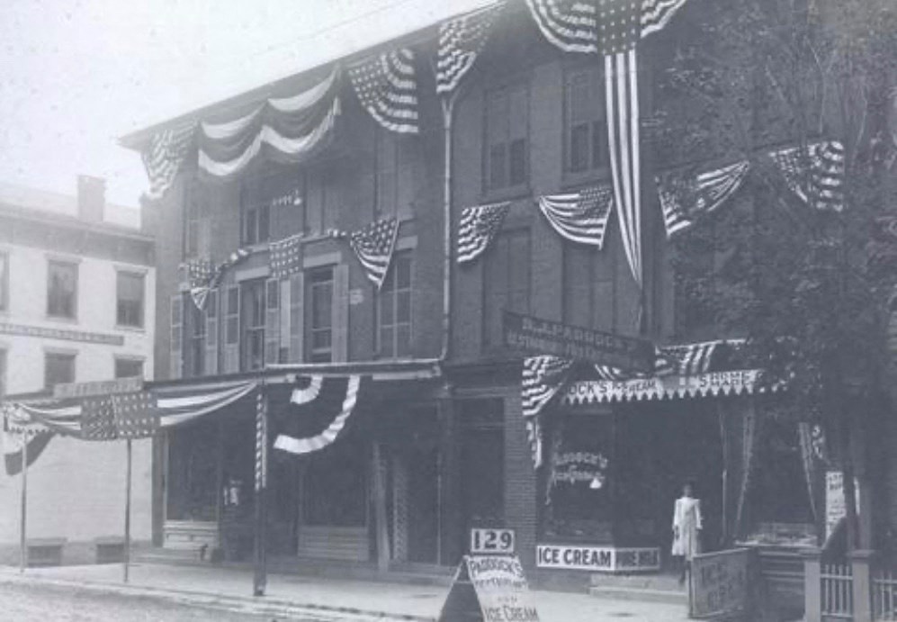 A black and white photo of a building with an ice cream shop on the ground floor.