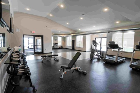 A gym with a variety of equipment including treadmills, weights, and exercise machines.
