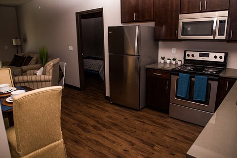 a kitchen and living room with stainless steel appliances and wooden floors